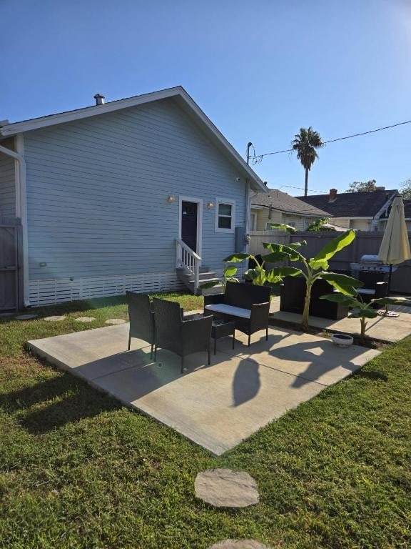 rear view of property with entry steps, a patio, and a lawn