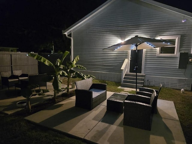 patio at night featuring entry steps, fence, and an outdoor hangout area