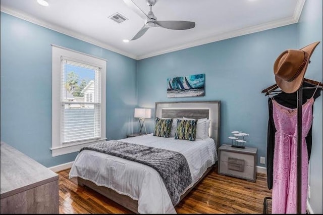 bedroom featuring visible vents, crown molding, ceiling fan, baseboards, and wood finished floors