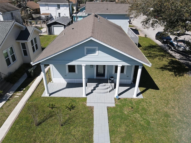 view of front facade featuring a residential view, a front yard, and roof with shingles