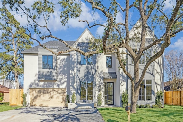 view of front of house featuring a front yard, an attached garage, driveway, and fence