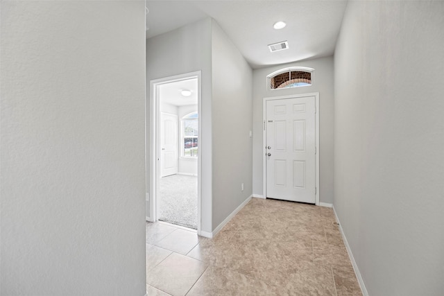 hallway with light tile patterned floors, visible vents, and baseboards