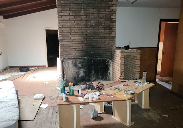 unfurnished living room featuring a brick fireplace and lofted ceiling with beams