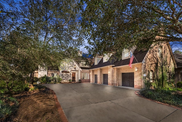 view of front of house with a garage, brick siding, and a shingled roof