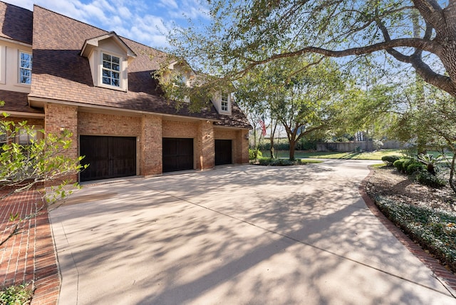 view of property exterior featuring a garage, brick siding, roof with shingles, and driveway