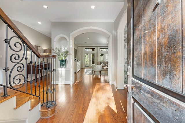 entryway featuring stairway, wood finished floors, recessed lighting, arched walkways, and ornamental molding