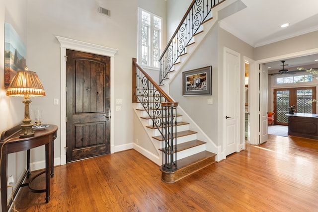 entrance foyer featuring visible vents, crown molding, baseboards, stairs, and wood finished floors