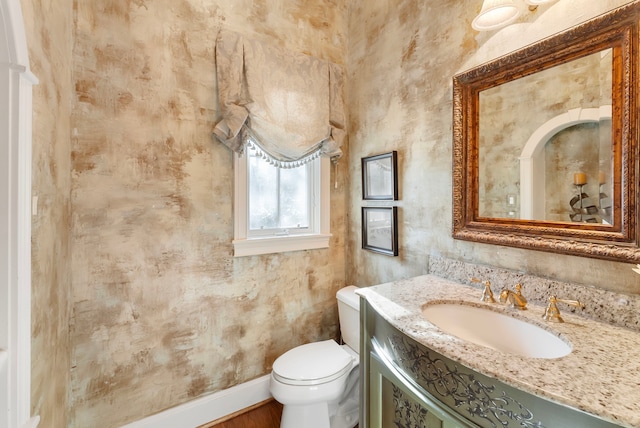 bathroom featuring baseboards, toilet, and vanity