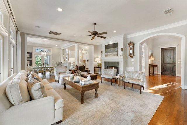 living area featuring visible vents, a tile fireplace, crown molding, and wood-type flooring