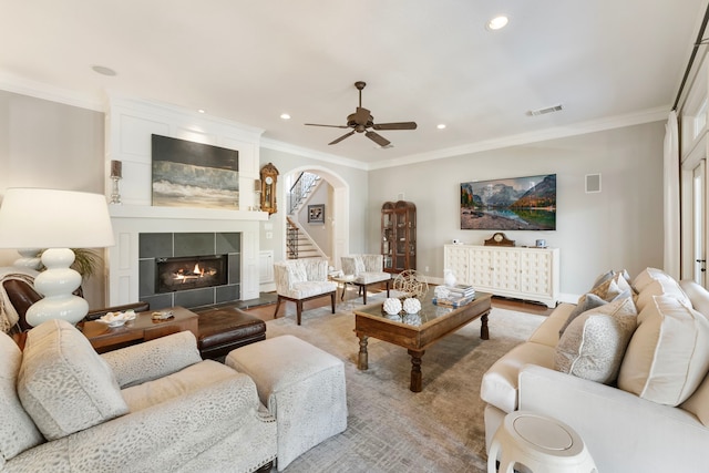 living area featuring visible vents, ornamental molding, arched walkways, a fireplace, and baseboards