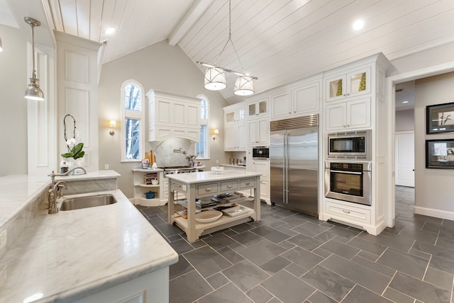 kitchen featuring a sink, white cabinets, glass insert cabinets, built in appliances, and beamed ceiling