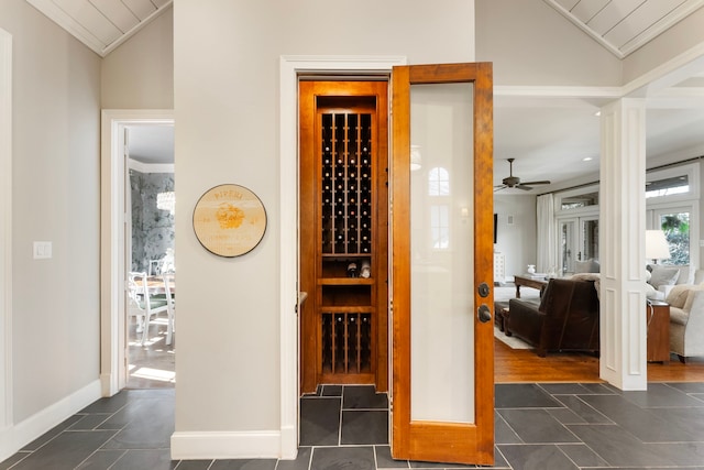 wine area with baseboards, dark tile patterned floors, and vaulted ceiling