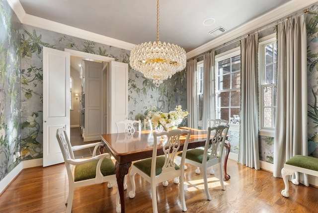 dining room featuring a chandelier, light wood-style flooring, wallpapered walls, and crown molding