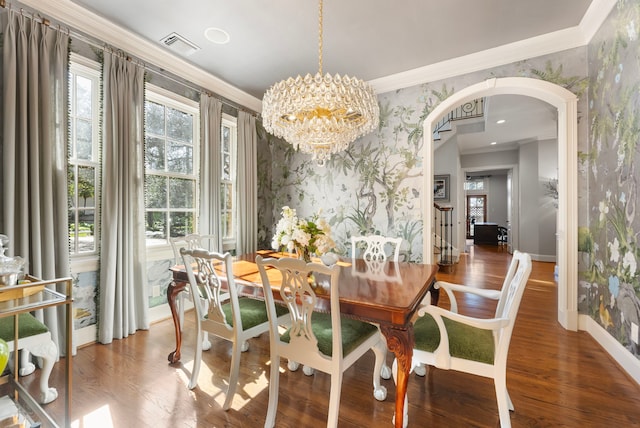 dining area with wood finished floors, arched walkways, crown molding, wallpapered walls, and baseboards