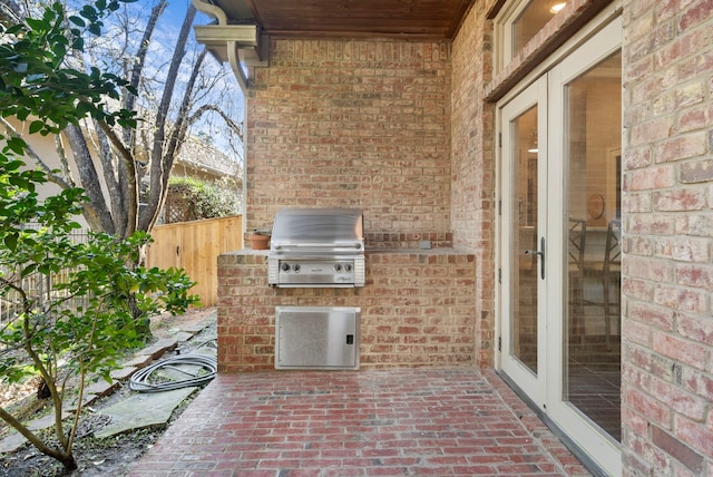 view of patio with area for grilling, a grill, and fence