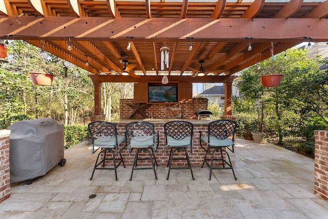 view of patio with outdoor dry bar, grilling area, a brick fireplace, and a pergola