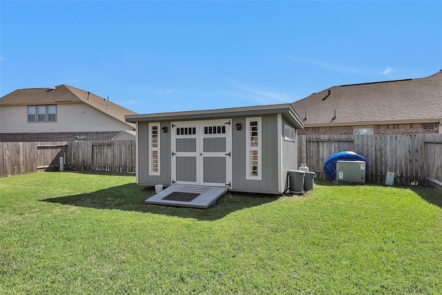 rear view of house with an outbuilding, a lawn, a fenced backyard, and a shed