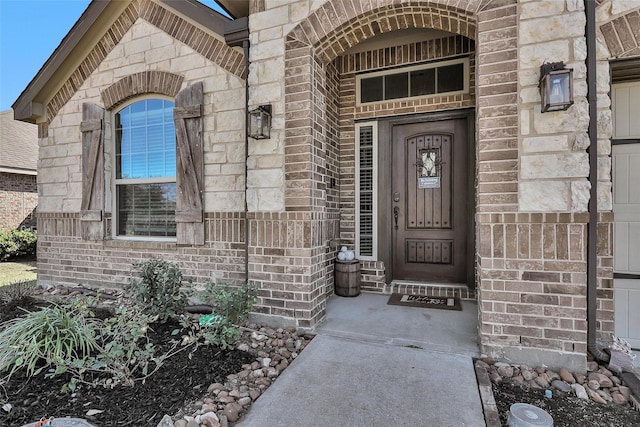 view of exterior entry featuring stone siding and brick siding