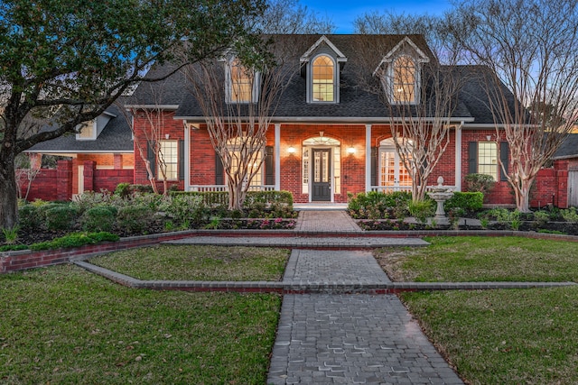 cape cod home featuring brick siding, a shingled roof, and a front lawn