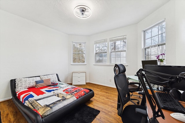 bedroom featuring wood finished floors, baseboards, and a textured ceiling