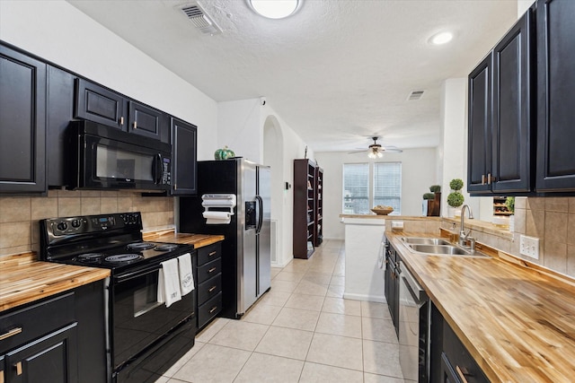 kitchen with a sink, black appliances, butcher block countertops, and dark cabinets