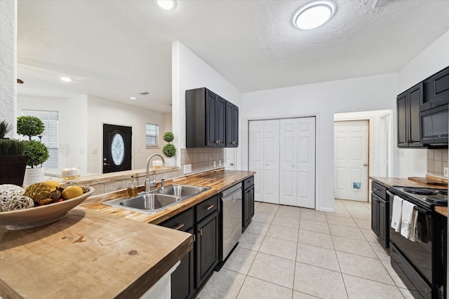 kitchen with tasteful backsplash, butcher block countertops, light tile patterned floors, black appliances, and a sink