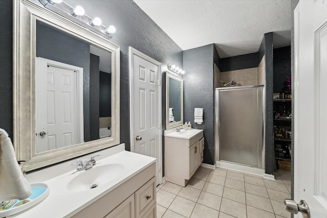 bathroom with a stall shower, a textured wall, tile patterned floors, a textured ceiling, and a sink