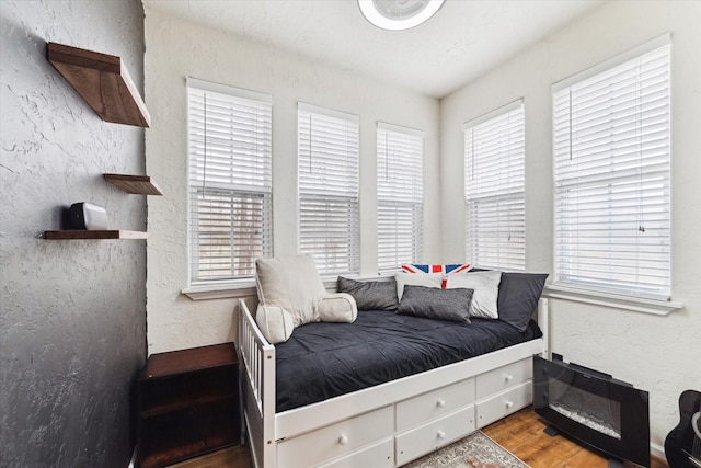 bedroom featuring wood finished floors and a textured wall