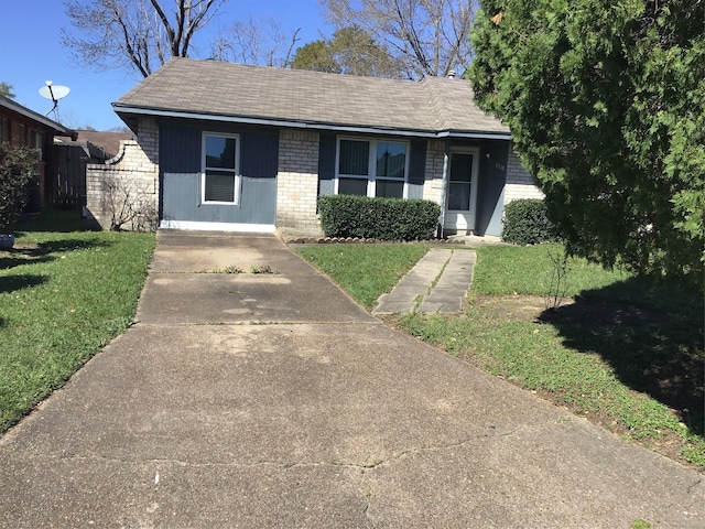 view of front of home featuring brick siding, a front lawn, and fence