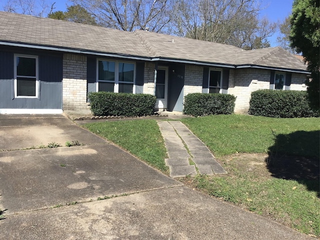 ranch-style house with a front lawn, brick siding, and roof with shingles