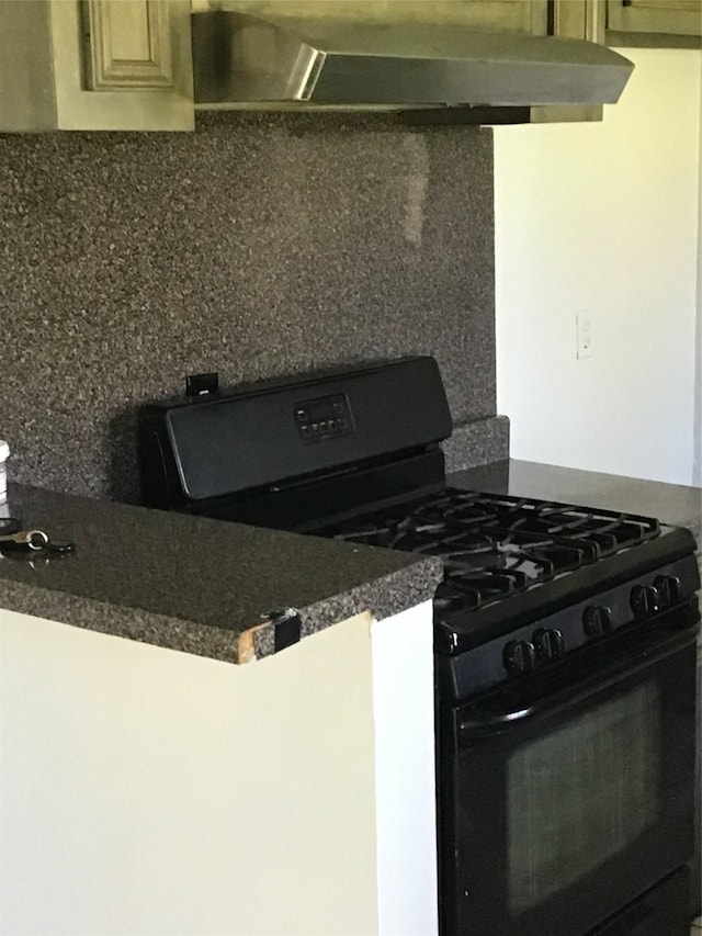 kitchen featuring decorative backsplash, dark countertops, black gas range oven, and under cabinet range hood