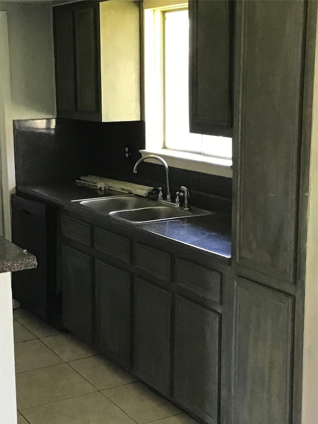 kitchen with dishwasher, dark countertops, light tile patterned flooring, and a sink