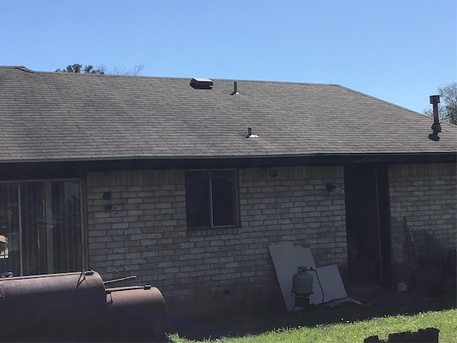 back of property featuring brick siding and a shingled roof