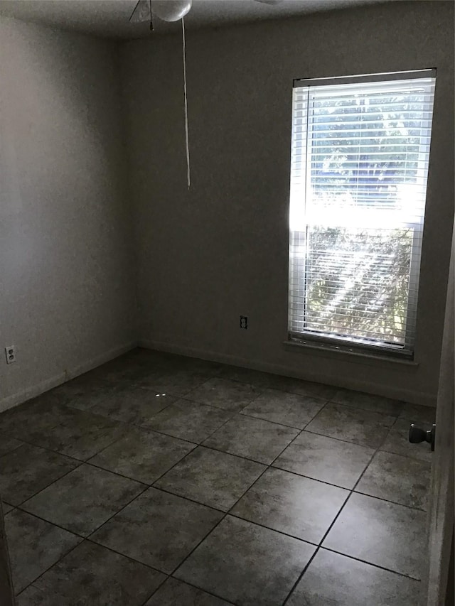 empty room with dark tile patterned flooring and baseboards