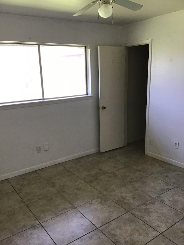 spare room featuring tile patterned floors, baseboards, and ceiling fan