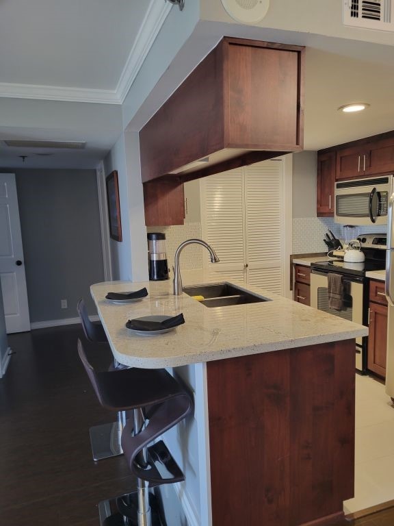 kitchen with visible vents, a sink, stainless steel appliances, crown molding, and decorative backsplash