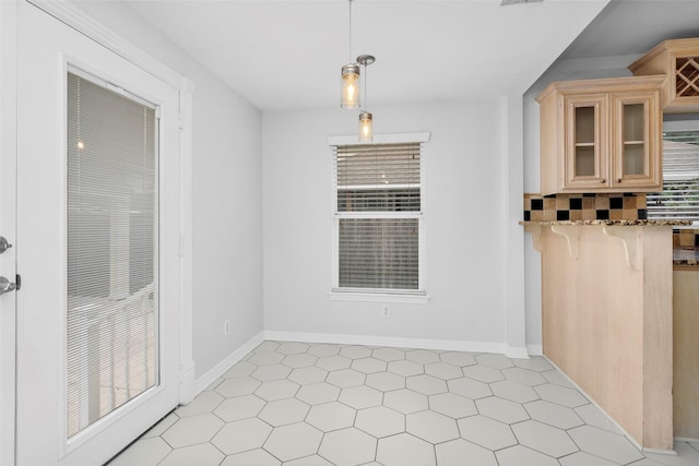 interior space featuring pendant lighting, stone countertops, a kitchen breakfast bar, glass insert cabinets, and baseboards