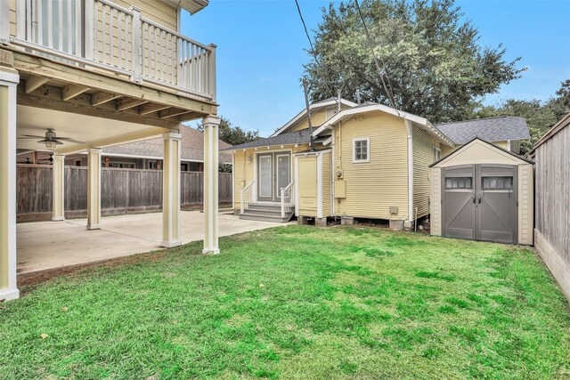 back of property with fence, entry steps, a yard, a patio area, and an outbuilding