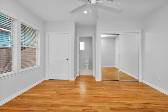 unfurnished bedroom with two closets, baseboards, light wood-style floors, and ceiling fan