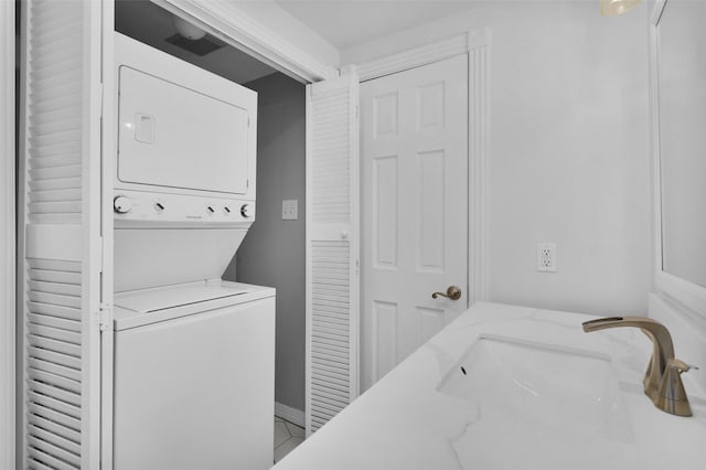 laundry room with laundry area, a sink, and stacked washer and dryer