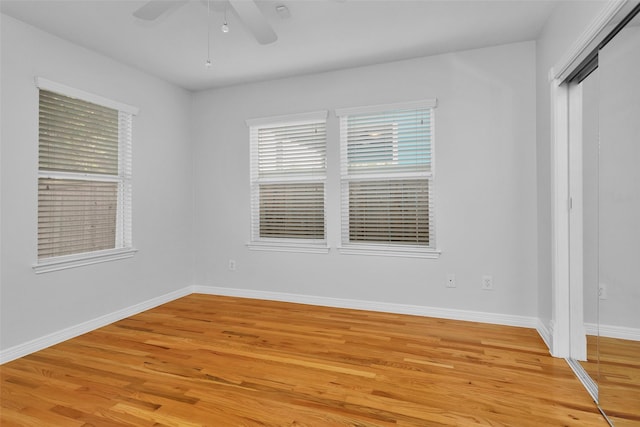 spare room featuring ceiling fan, baseboards, and light wood-style floors