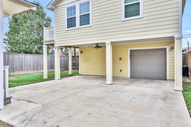 garage featuring a ceiling fan, concrete driveway, and fence