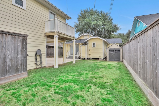 view of yard featuring entry steps, a fenced backyard, a balcony, an outdoor structure, and a storage unit