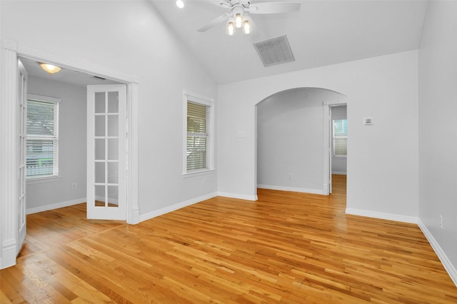 empty room with a wealth of natural light, visible vents, arched walkways, and ceiling fan