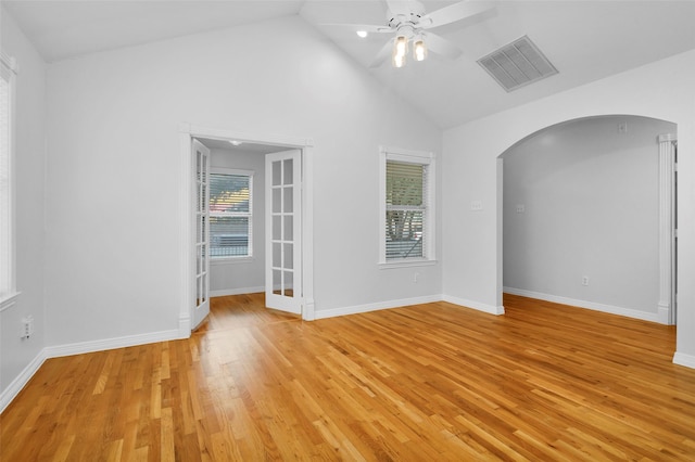 unfurnished room with visible vents, arched walkways, light wood finished floors, baseboards, and ceiling fan