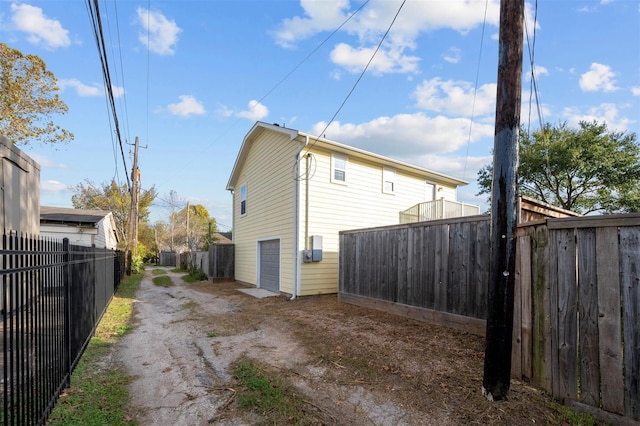 back of house featuring dirt driveway, an attached garage, and fence