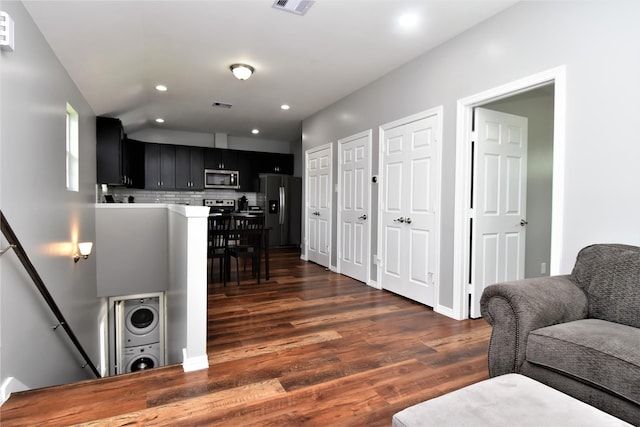 living room featuring recessed lighting, visible vents, stacked washer and clothes dryer, and dark wood-style flooring