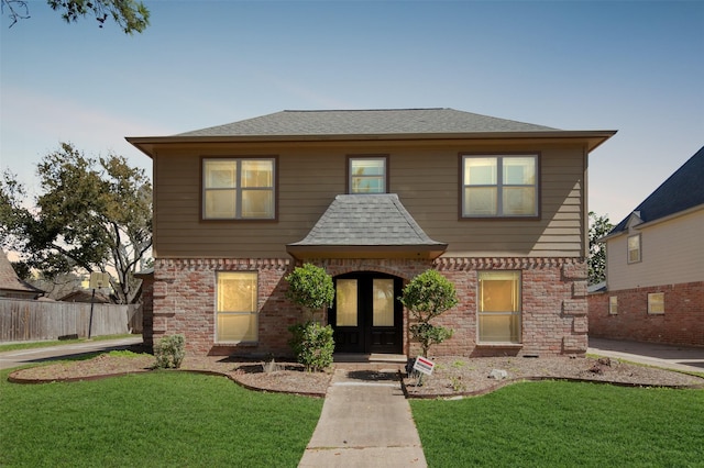 view of front of property with a front lawn, french doors, brick siding, and roof with shingles