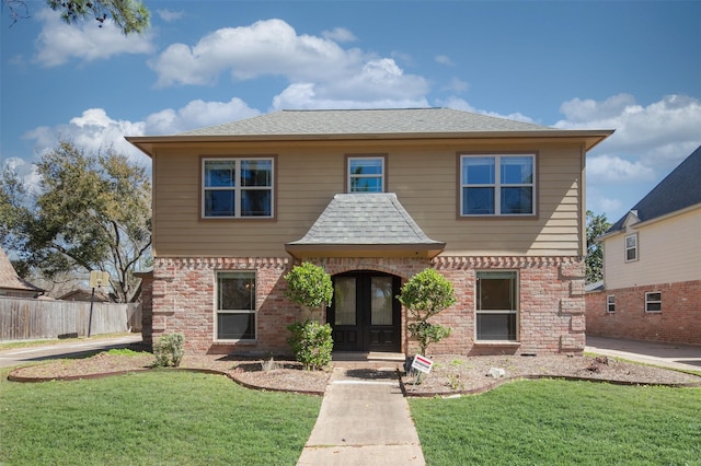 view of front of house with french doors, brick siding, a front yard, and a shingled roof