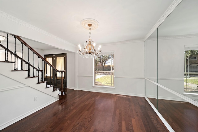 unfurnished dining area featuring crown molding, baseboards, a chandelier, stairway, and wood finished floors